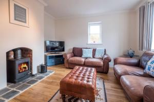 sala de estar con muebles de cuero y chimenea en April Cottage en Aldeburgh