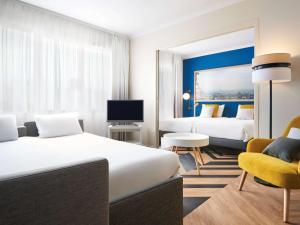 a hotel room with two beds and a chair at Aparthotel Adagio Porte de Versailles in Paris