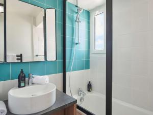 a bathroom with a sink and a tub and a mirror at Aparthotel Adagio Porte de Versailles in Paris