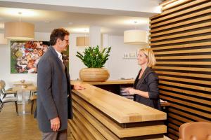 Ein Mann und eine Frau stehen an einem Tresen in der Unterkunft Hotel am Peterstor in Regensburg