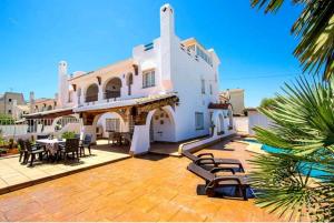 a large white building with tables and chairs on a patio at R116 Casa adosada con piscina privada en Cunit in Cunit
