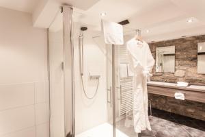 a bathroom with a shower and a robe on a rack at Romantik Hotel Alte Münze in Goslar