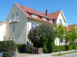 een wit huis met een rood dak bij Villa Silva - Leuchtturmblick in Kühlungsborn