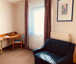 a living room with a couch and a table and a window at Akzent Congresshotel Hoyerswerda in Hoyerswerda