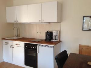 a kitchen with white cabinets and a black dishwasher at Haus an der Therme in Bad Endorf