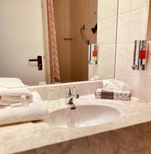 a bathroom with a sink and a mirror and towels at Akzent Congresshotel Hoyerswerda in Hoyerswerda