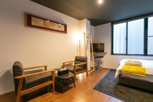 una camera con letto, sedie e televisore di Noyado Uehonmachi ad Osaka