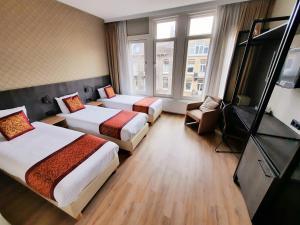 a hotel room with two beds and a television at Hotel Washington in Amsterdam