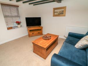 a living room with a blue couch and a television at 3 Eden Lodge in Kirkby Stephen