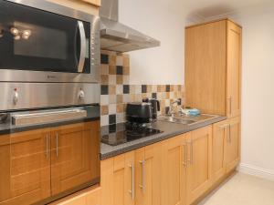 a kitchen with wooden cabinets and a microwave at 2 Eden Lodge in Kirkby Stephen