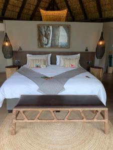 a bedroom with a large bed with a bench in it at Laluka Safari Lodge - Welgevonden Game Reserve in Welgevonden Game Reserve