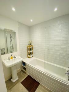 a white bathroom with a tub and a sink at Elegant Spacious Apartment in Heart of St Leonards in Hastings