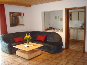 a living room with a black leather couch and a table at Ferienwohnung Glückstein in Großeibstadt