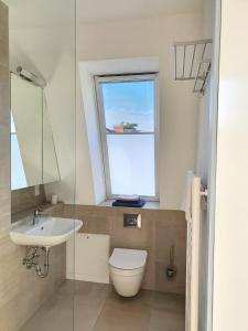 a bathroom with a toilet and a sink and a window at südausgerichtetes Apartment SüdWest Kleinmachnow in Kleinmachnow