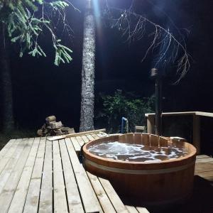 una bañera de hidromasaje en una terraza de madera junto a un árbol en Cabañas Agua Viva, en Molco