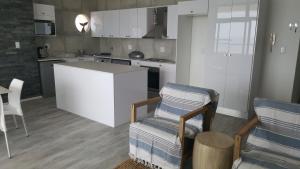 a kitchen with white cabinets and two chairs and a table at Point Village Accommodation - Santos 23 in Mossel Bay