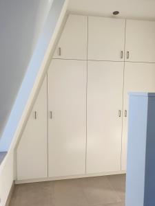 a white loft kitchen with white cabinets and a staircase at südausgerichtetes Apartment SüdWest Kleinmachnow in Kleinmachnow