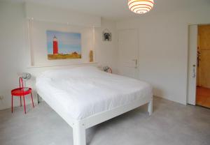 a white bedroom with a white bed and a red stool at Bed & Bad Soet Texel in Den Burg
