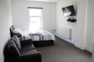 ein Schlafzimmer mit einem Bett, einem Stuhl und einem TV in der Unterkunft Bursar Street 21 in Cleethorpes