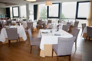 un restaurante con mesas y sillas blancas y ventanas en Parador de Soria, en Soria