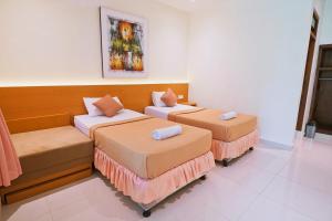 a room with two beds and a couch at Sari Bali Cottage in Kuta