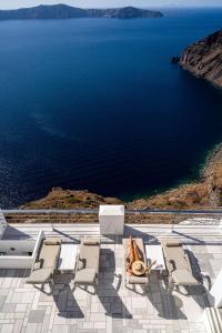 a patio with chairs and a view of the water at Homeric Poems in Fira