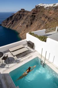 a person in a swimming pool with a view of the ocean at Homeric Poems in Fira