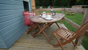 uma mesa de madeira e cadeiras num deque em Showman's Hut Westcote em Hawick