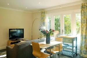 a living room with a couch and a table with flowers at Immaculate Quiet Coach House in Garden Birmingham in Birmingham