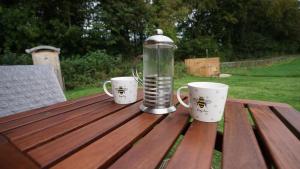 two coffee cups and a thermos on a wooden table at Unique Off- Grid Beehive Pod at Westcote Glamping in Hawick