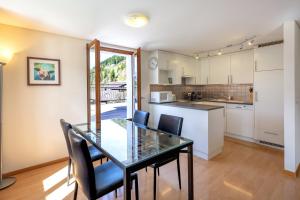 cocina con mesa de cristal y sillas negras en Luxury Alpine Apartment, en Château-d'Oex