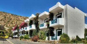 a large white building with balconies on a street at Armonia Hotel in Matala