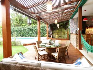 un patio con mesa y sillas en una terraza en Casa linda c Piscina e WiFi na Praia de Camburi - SP, en São Sebastião