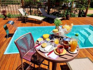 a table with food and drinks on it next to a pool at Vila Lua de Taipu - Taipu de Fora in Barra Grande