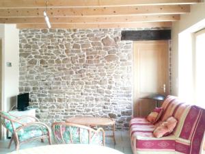 a living room with a stone wall with a couch and chairs at Maison d'une chambre avec jardin amenage et wifi a Plehedel a 5 km de la plage in Pléhédel