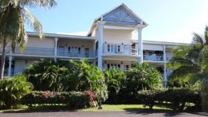 a large white building with palm trees in front of it at Appartement moderne à Saint-François 90 m² avec piscine partagée in Saint-François