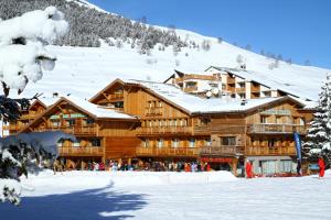 a large wooden lodge with snow on the roof at Hotel Les Mélèzes in Les Deux Alpes