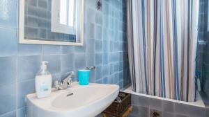 シッチェスにあるSunny Apartmentsの青いタイル張りのバスルーム(シンク、シャワー付)