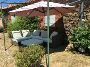 - un canapé sous un parasol dans la cour dans l'établissement Maison d'une chambre avec piscine privee jardin et wifi a Montauriol, à Montauriol