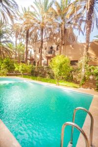 a swimming pool in front of a house with palm trees at 7 bedrooms house with shared pool terrace and wifi at Zagora in Zagora