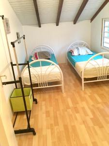 two beds in a room with wooden floors at Maison de 2 chambres avec terrasse amenagee et wifi a Pointe Noire a 2 km de la plage in Pointe-Noire