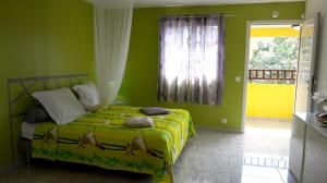 Un dormitorio con una cama con paredes verdes y una ventana en Appartement d'une chambre a Deshaies a 900 m de la plage avec piscine partagee jardin clos et wifi en Deshaies