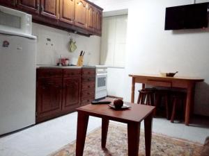 uma cozinha com uma mesa e uma pequena cozinha com um frigorífico em One bedroom appartement with city view enclosed garden and wifi at Alvoco da Serra em Alvoco da Serra