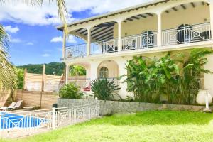 a house with a balcony and a swimming pool at Spacieuse villa à Deshaies avec piscine privée in Deshaies