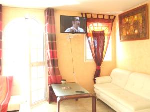 a living room with a white couch and a tv at Spacieuse villa à Deshaies avec piscine privée in Deshaies