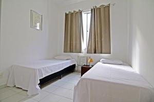 2 camas en una habitación blanca con ventana en Rio Spot Homes Leblon D026, en Río de Janeiro