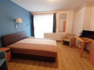 a bedroom with a bed and a chair and a window at Szilvió in Gyenesdiás