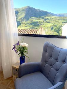 una silla azul y un jarrón con flores en una ventana en 2 bedrooms house with wifi at Viguera, en Viguera