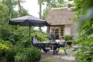 two people sitting at a table under an umbrella at Huize Florinata in Voorthuizen