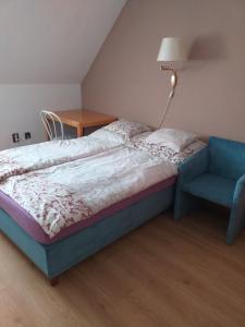 a bedroom with a bed and a blue chair at Szilvi&oacute; in Gyenesdi&aacute;s